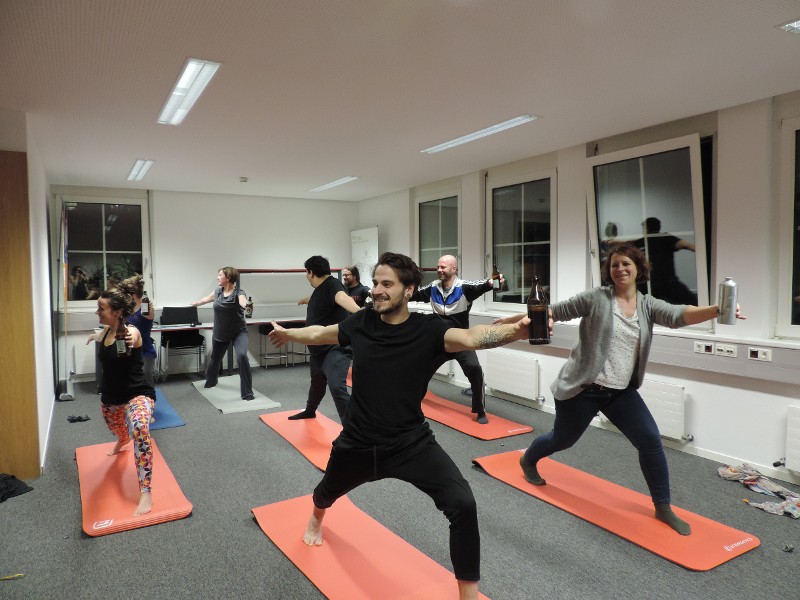Mitarbeitende beim Bier-Yoga auf roten Gymnastikmatten