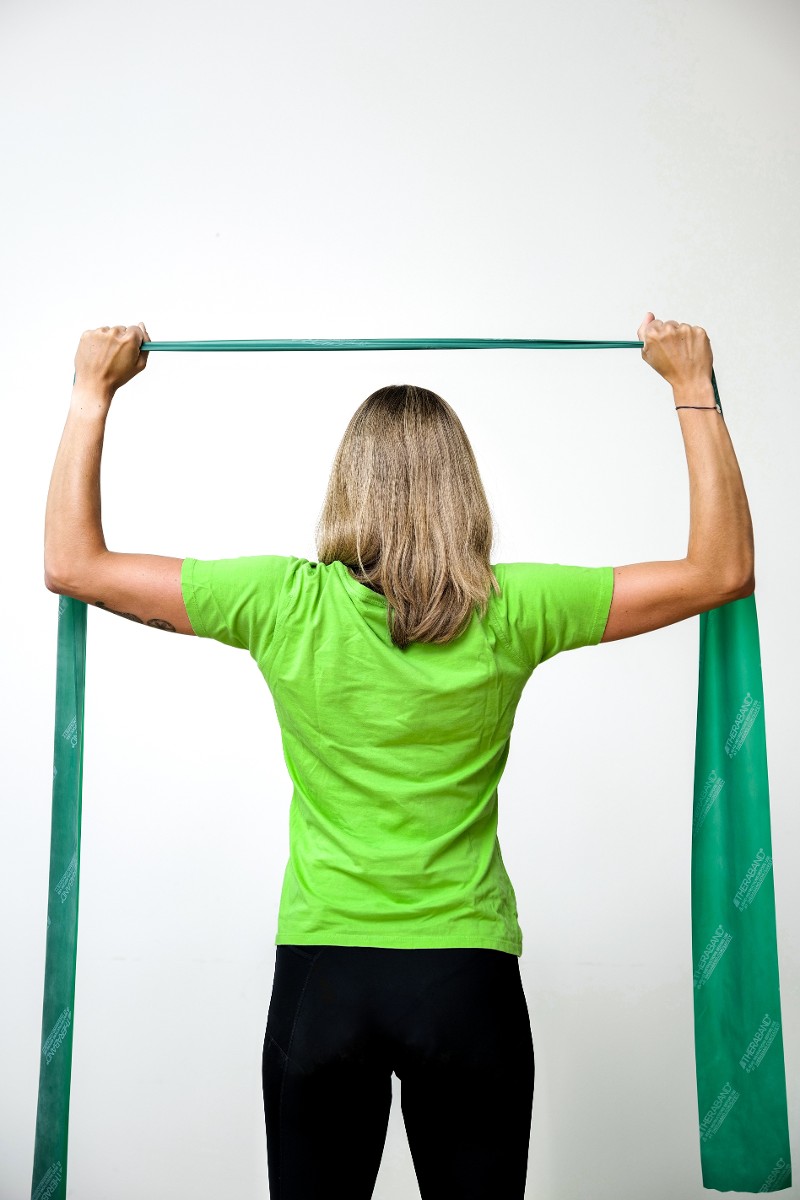 Frau trainiert mit Theraband den Latissimus